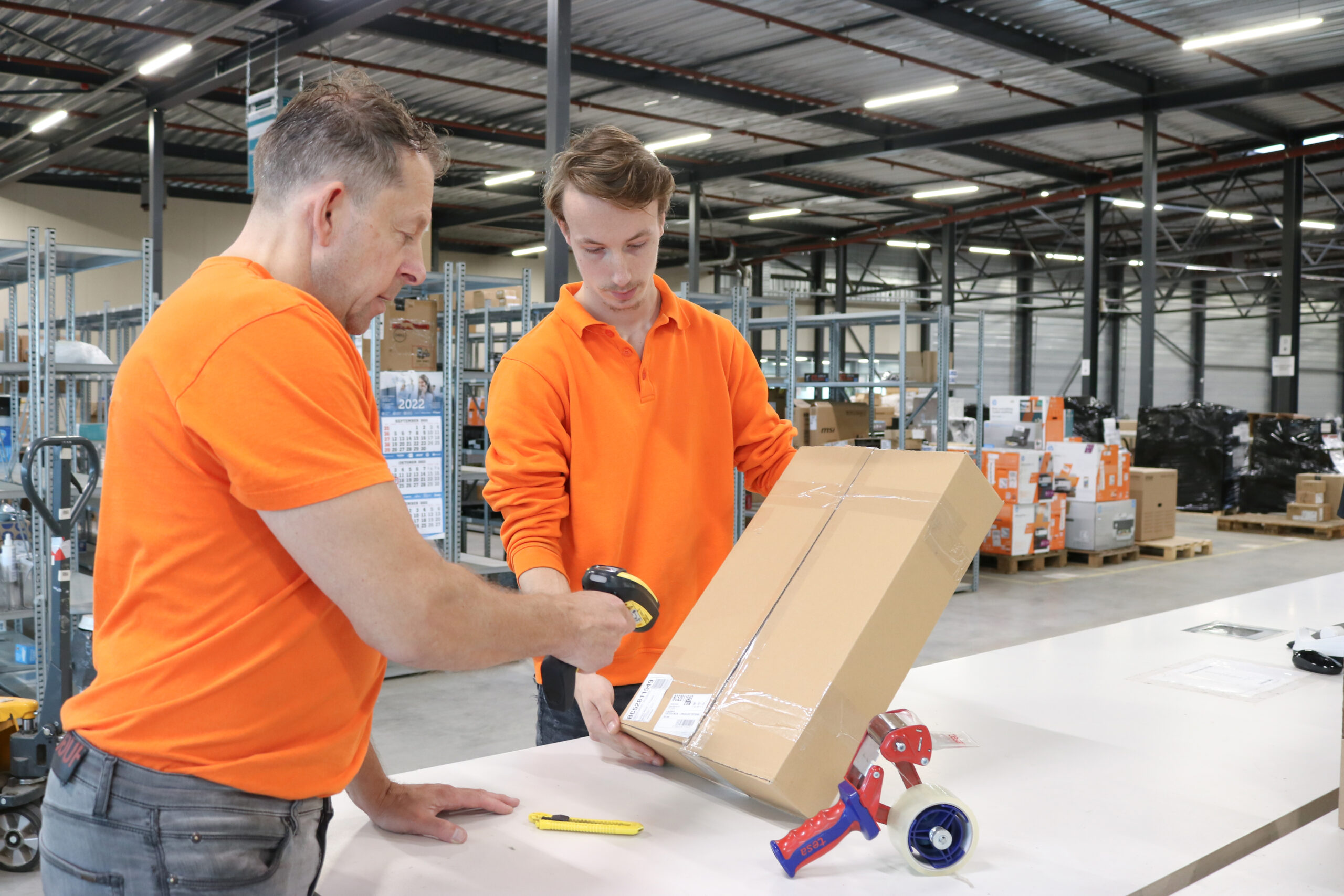 Ene medewerker van Yours houdt de doos vast en de ander scant de EAN-code op de doos